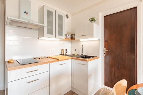 - une cuisine avec des placards blancs et une porte en bois dans l'établissement Le Lamparo entre Port et Mer, à Port-Leucate