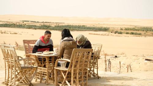 a group of people sitting at a table in the desert at Karam Siwa Camp in Siwa