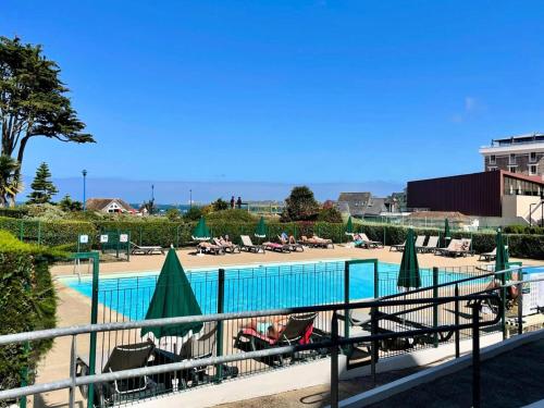 - une piscine avec des chaises longues et des parasols dans l'établissement Résidence L'archipel - Appartement au pied de la plage de Trestraou MAE-3554, à Perros-Guirec