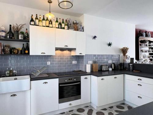 - une cuisine avec des placards blancs et des bouteilles de vin dans l'établissement Résidence G78-tregastel - Maison avec jardin près du Coz Pors à Trégastel MAE-3574, à Trégastel