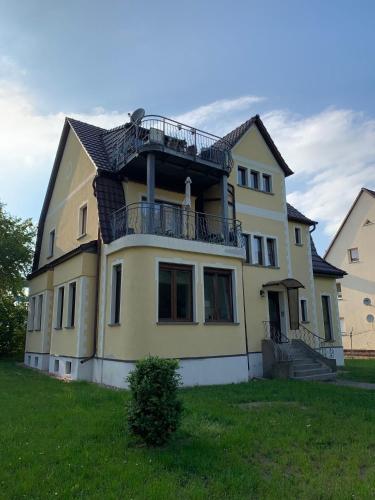 a yellow house with a balcony on top of it at Ferienwohnung Ehrich in Stöbnitz