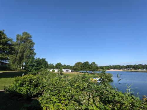 vistas a un lago con casas en el fondo en Luxuswohnwagen Hecht am Kransburger See 001, en Kransburg