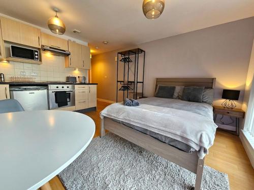 a bedroom with a bed and a table and a kitchen at Modern studio apartment in Gunwharf in Portsmouth