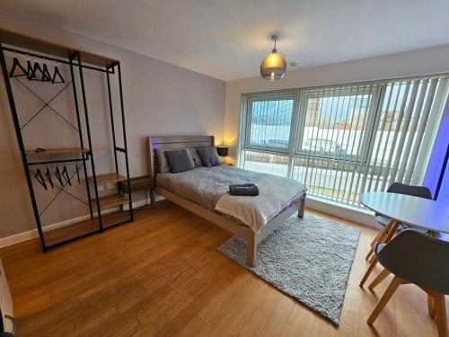 1 dormitorio con cama, mesa y ventana en Modern studio apartment in Gunwharf, en Portsmouth