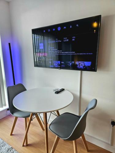 a white table and two chairs and a tv on a wall at Modern studio apartment in Gunwharf in Portsmouth