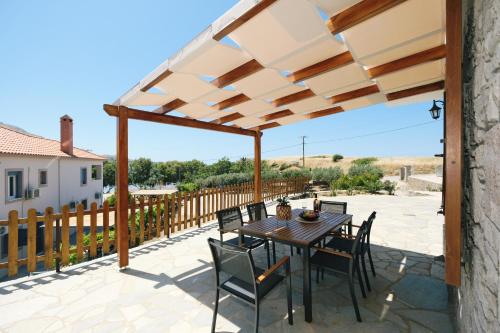 a patio with a wooden pergola and a table and chairs at Nerea Apartments in Agios Ioannis Kaspaka