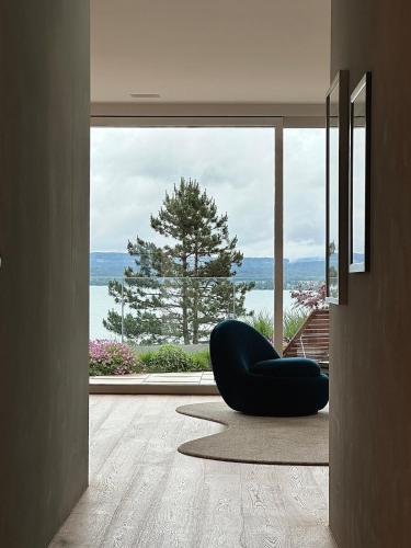 a living room with a chair and a large window at LAKEVIEW - a design holiday home in Berlingen