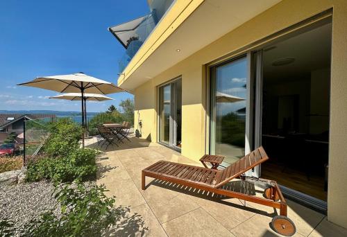 a wooden bench sitting on a patio with an umbrella at LAKEVIEW - a design holiday home in Berlingen