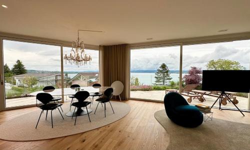 a living room with a table and chairs and a large window at LAKEVIEW - a design holiday home in Berlingen
