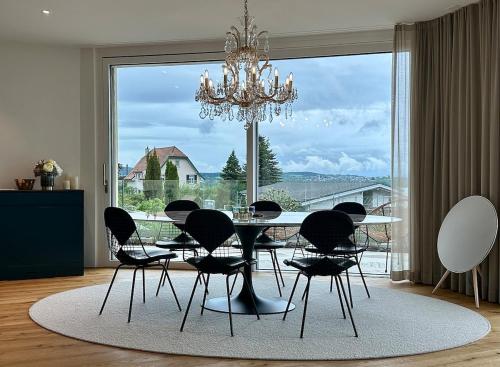 a dining room with a table and chairs and a large window at LAKEVIEW - a design holiday home in Berlingen