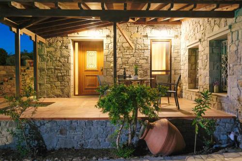 a stone house with a wooden porch with a table at Nerea Apartments in Agios Ioannis Kaspaka
