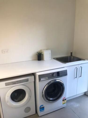 a kitchen with a washing machine and a sink at Hosts on the Coast Whanga Escape in Whangamata
