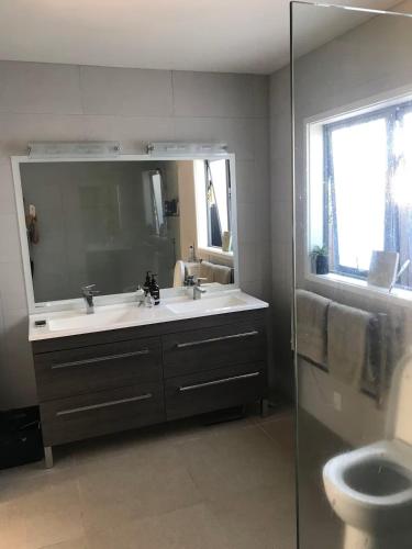 a bathroom with a sink and a mirror and a toilet at Hosts on the Coast Whanga Escape in Whangamata