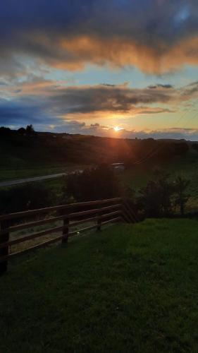 a sunset over a field with a wooden fence at The Old Homestead - direct greenway access in Maas