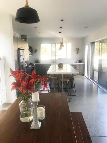 a kitchen with a table with a vase of flowers on it at Hosts on the Coast Whanga Escape in Whangamata