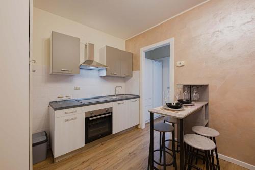 a kitchen with white cabinets and bar stools at Bilocale Chic vicino al Teatro in Udine