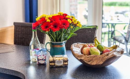 a table with a vase of flowers and a bowl of fruit at 4 Sterne-Terrassen-Fewo "Heimathaven" direkt am Ostseestrand inkl Schwimmbad in Kronsgaard