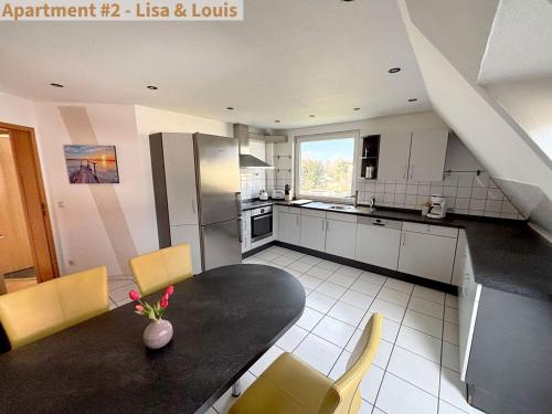 a kitchen with a black table and yellow chairs at Grosse Comfort-Ferienwohnungen Haus Bonni in Celle