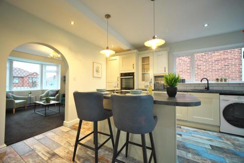 a kitchen with a counter and chairs in a room at Luxury Bungalow, 3 bedrooms, 5 beds, sleeps 8, transport links, parking, Wi-Fi in South Elmsall