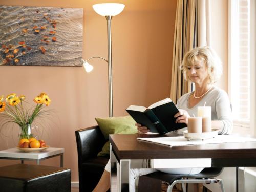 une femme assise à une table en train de lire un livre dans l'établissement ancora Marina Haus 2 Nr 07, Typ 2, à Neustadt in Holstein