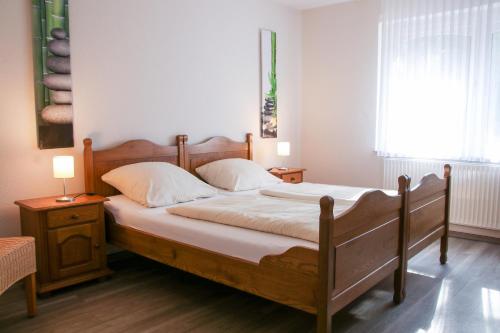 a bedroom with a wooden bed with white sheets and pillows at Familienhof Brüning - Terrassenwohnung in Meppen