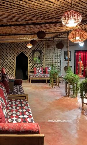 a living room with a couch and tables and chandeliers at Riad La Perle Tamnougalte in Agdz