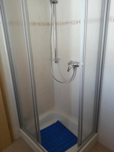 a shower with a glass door with a blue floor at Ferienhaus Klapötke in Dorum