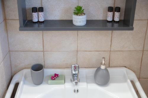 a bathroom sink with a cup and a mug on it at Aristeas Studio in Ornos