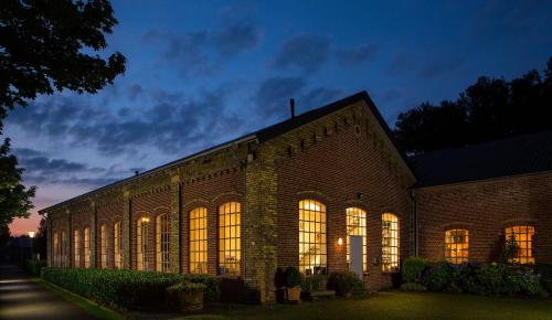 a large brick building with illuminated windows at night at LokoMotel-Wohnung, Luxus Ferienwohnung im Lokschuppen in Stadtlohn