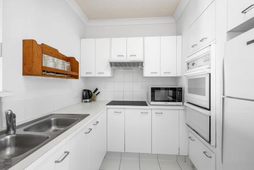 a white kitchen with white cabinets and a sink at 6- 'Cote D'Azur' 6 Douglas Street Sunshine Beach in Sunshine Beach