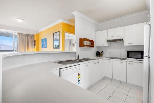 a white kitchen with white cabinets and a sink at 6- 'Cote D'Azur' 6 Douglas Street Sunshine Beach in Sunshine Beach