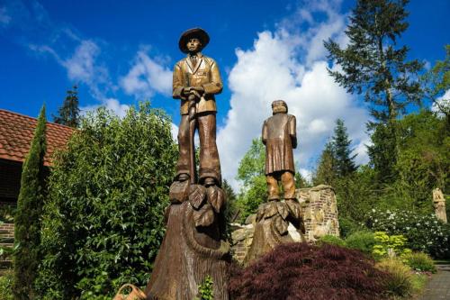 una estatua de dos hombres de pie sobre un tocón de árbol en Waldgasthof Röckers-Ferienwohnung Hahnenkrai, en Meppen