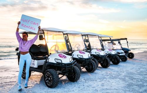 a man holding a sign in front of four atvs on the beach at Luxury Penthouse, Ocean Views, Rare Rooftop Sundeck, Private Access to Beach in Siesta Key