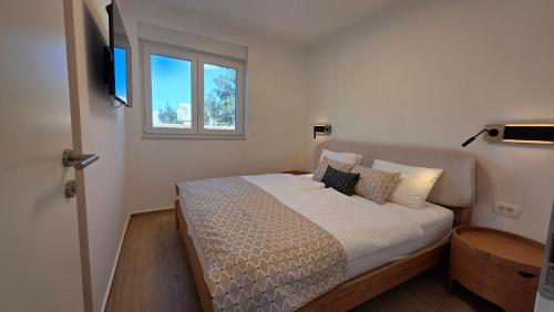 a bedroom with a bed with white sheets and a window at Residence Giardino in Ugljan