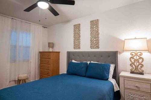 una camera con letto blu e ventilatore a soffitto di Ranch Glam Townhome with Indoor Fireplace a El Paso