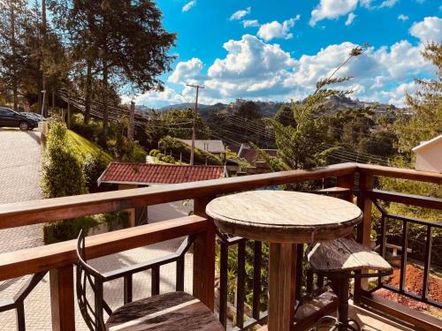a wooden deck with a table and chairs on a balcony at Pousada Cantinho da Serra in Campos do Jordão
