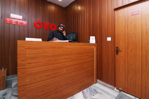 a man is standing behind a wooden door at Hotel O Meerut International in Meerut
