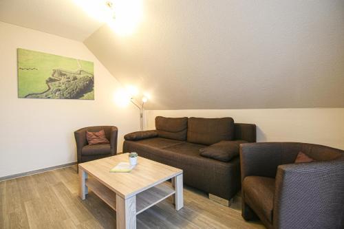 een woonkamer met een bank, twee stoelen en een tafel bij Familienhof Brüning - Stadtblick in Meppen