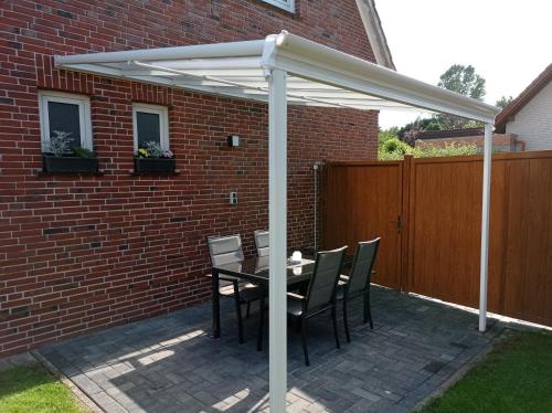 a patio with a table and chairs under a white pergola at Ferienwohnung Gerda in Lathen