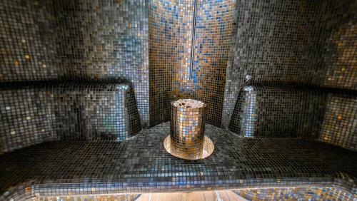 a vase in the corner of a room with tiles at Hotel Bucura in Călimăneşti