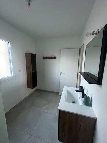 une salle de bain blanche avec un lavabo et un miroir dans l'établissement Les Lavandières, à Barbeville