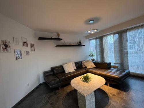 a living room with a leather couch and a table at Isenbüttel Ferienwohnung in Isenbüttel