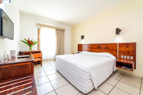a bedroom with a bed and a desk and a television at Hotel Castillo Huatulco & Beach Club in Santa Cruz Huatulco