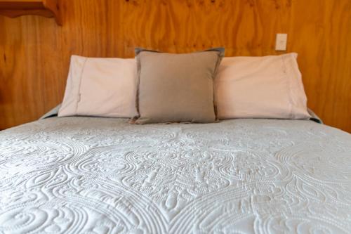 a bed with white sheets and pillows at Tūī Guesthouse in Cooks Beach
