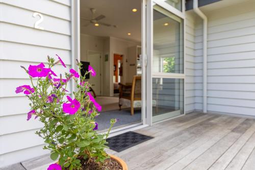 a front porch with purple flowers on a house at Tūī Guesthouse in Cooks Beach