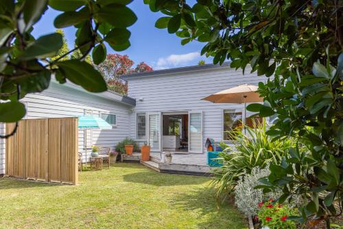a house with a patio and an umbrella at Tūī Guesthouse in Cooks Beach