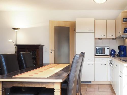 a kitchen with a wooden table and black chairs at FeWo 40 "Haus Kormoran - W3" in Prerow