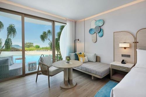 a hotel room with a bed and a table and a couch at Veranda Resort Phuket, Autograph Collection in Panwa Beach