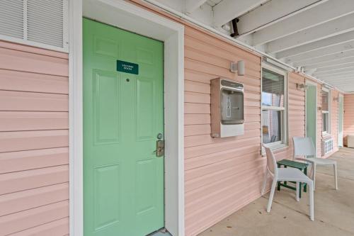 a green door on a pink house with a chair at TreeHouse Lodge Walk to Beach Pet-Friendly 103 in Myrtle Beach