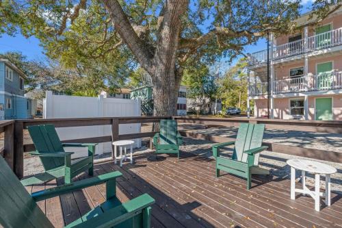 a deck with green chairs and a table and a tree at TreeHouse Lodge Walk to Beach Pet-Friendly 103 in Myrtle Beach